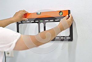 Technician to measure water level Of the TV mounting device on the wall Installation of steel plates with TV for weight loss