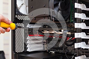 Technician use a screwdriver to attach the graphics card to the system case.