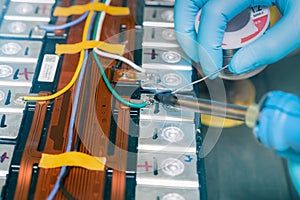 Technician use soldering iron to solder metal and wire of lithium-ion rechargeable battery. Repair module of Li-ion battery.