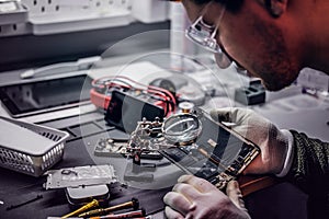 Technician uses a magnifying glass to carefully inspect the internal parts of the smartphone in a modern repair shop