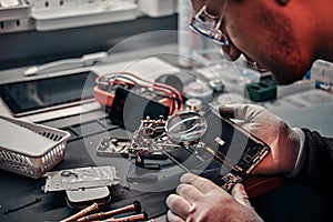 Technician uses a magnifying glass to carefully inspect the internal parts of the smartphone in a modern repair shop