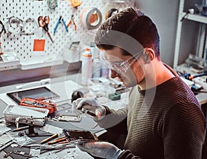 Technician uses a magnifying glass to carefully inspect the internal parts of the smartphone in a modern repair shop