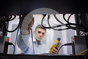 Technician using cable tester while fixing server