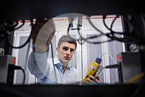 Technician using cable tester while fixing server