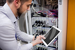 Technician using digital tablet while analyzing server