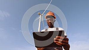 Technician using digital tablet while controlling working process of wind turbines outdoors. The concept of
