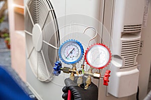 Technician using manifold gauge measuring tool check pump filling home air conditioner and checking maintenance heat fix repair