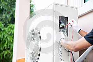 Technician using measuring equipment checking electric at circuit breaker on outdoor air compressor unit after install