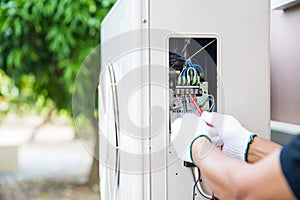 Technician using measuring equipment checking electric at circuit breaker on outdoor air compressor unit after install and check r