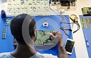 Technician using multimeter with computer electronics parts
