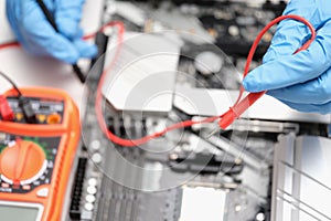 Technician using voltmeter to measure voltage on computer motherboard