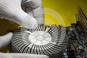 A technician in white antistatic gloves assembling cooling radiator onto the computer graphic card photo