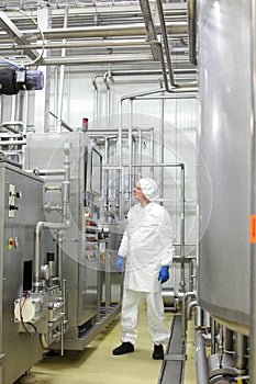 technician in white coveralls and cap controlling industrial process in plant