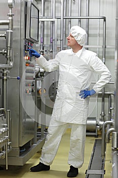 Technician in white coveralls and cap controlling industrial process in plant