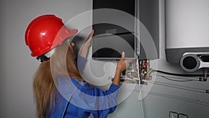 Technician woman unscrew bolt with screwdriver front panel of gas heating boiler