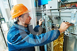 Technician worker adjusting elevator mechanism of lift photo