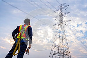 A Technician or Worker holding a safety helmet and gloves wear fall arrestor device for worker with hooks for safety body harness