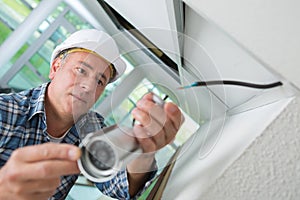 Technician worker installing video surveillance camera on wall