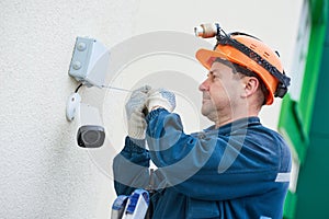 Technician worker installing video surveillance camera on wall