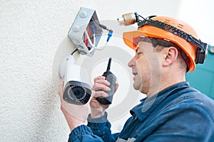 Technician worker installing video surveillance camera on wall