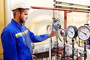 Technician worker on oil and gas refinery checks pressure manometers.