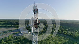 Technician worker servicing cellular antenna, drone view of telecommunication system tower