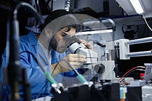 Technician working on circuit board under microscope in lab