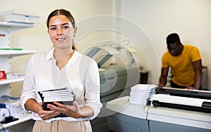 Technician working of printing house with stack of notebooks in her hands