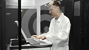 IT Technician Works on a compuiter in Big Data Center full of Rack Servers. He Runs Diagnostics and Maintenance Stets up