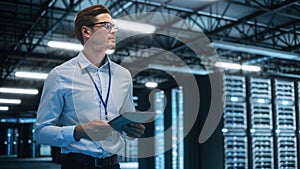 IT Technician Works on Tablet Computer in Big Data Center at Night. He Runs Diagnostics and Mainte