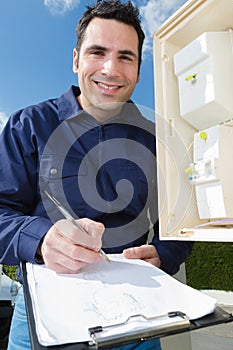 Technician writing reading electricity meter on clipboard