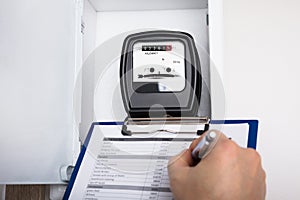 Technician Writing Reading Of Meter On Clipboard