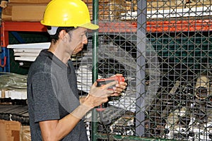 Technician with yellow helmet standing and driller in hand and working in area.