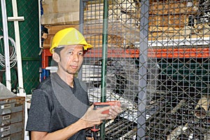 Technician with yellow helmet standing and driller in hand and working in area.