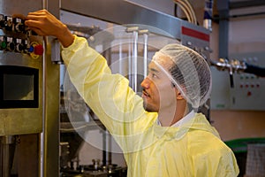 Technician young man adjust control panel of machine in factory for optimal performance.