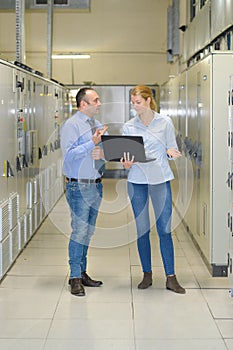 technicians discussing over laptop in server room