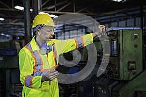 Technicians and engineers are working on machines in a factory. Caucasian man Mechanical Engineer holding tablet and checking