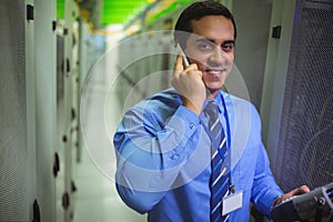 Technicians talking on mobile phone while analyzing server