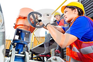 Technicians working on valve in factory or utility