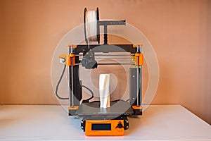 Technological hi-teg tool for making new things. A black and red 3D printer at work. The object is created by laying down