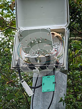 Technological infrastructure: Fiber optic distribution box on a metal pole between multicolored braided wires