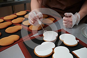 Technological process of production of gingerbread. The confectioner corrects the white glaze applied to the