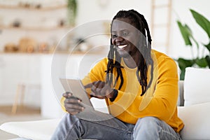 Technologies For Leisure. Black Happy Man Using Digital Tablet At Home