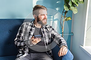 Technologies and leisure concept - Handsome man using smartphone at home.
