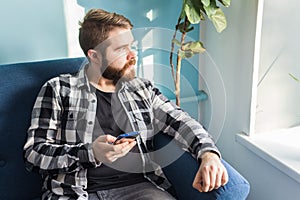 Technologies and leisure concept - Handsome man using smartphone at home.