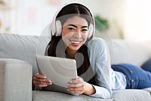 Technologies For Leisure. Korean Girl With Digital Tablet And Headphones At Home