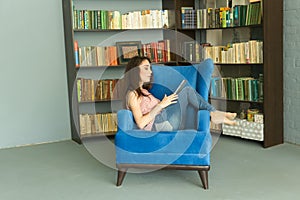 Technologies, people concept - young girl sitting on a chair and watching the tablet or surfing the net near the