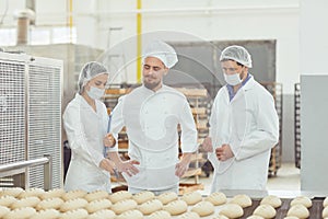 Technologist and baker inspect the bread production line at the bakery photo