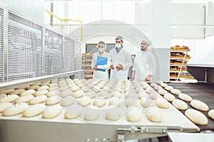 Technologist and baker inspect the bread production line at the bakery