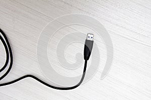 Technology black USB cable on white wooden table seen from above with texture background and space for text